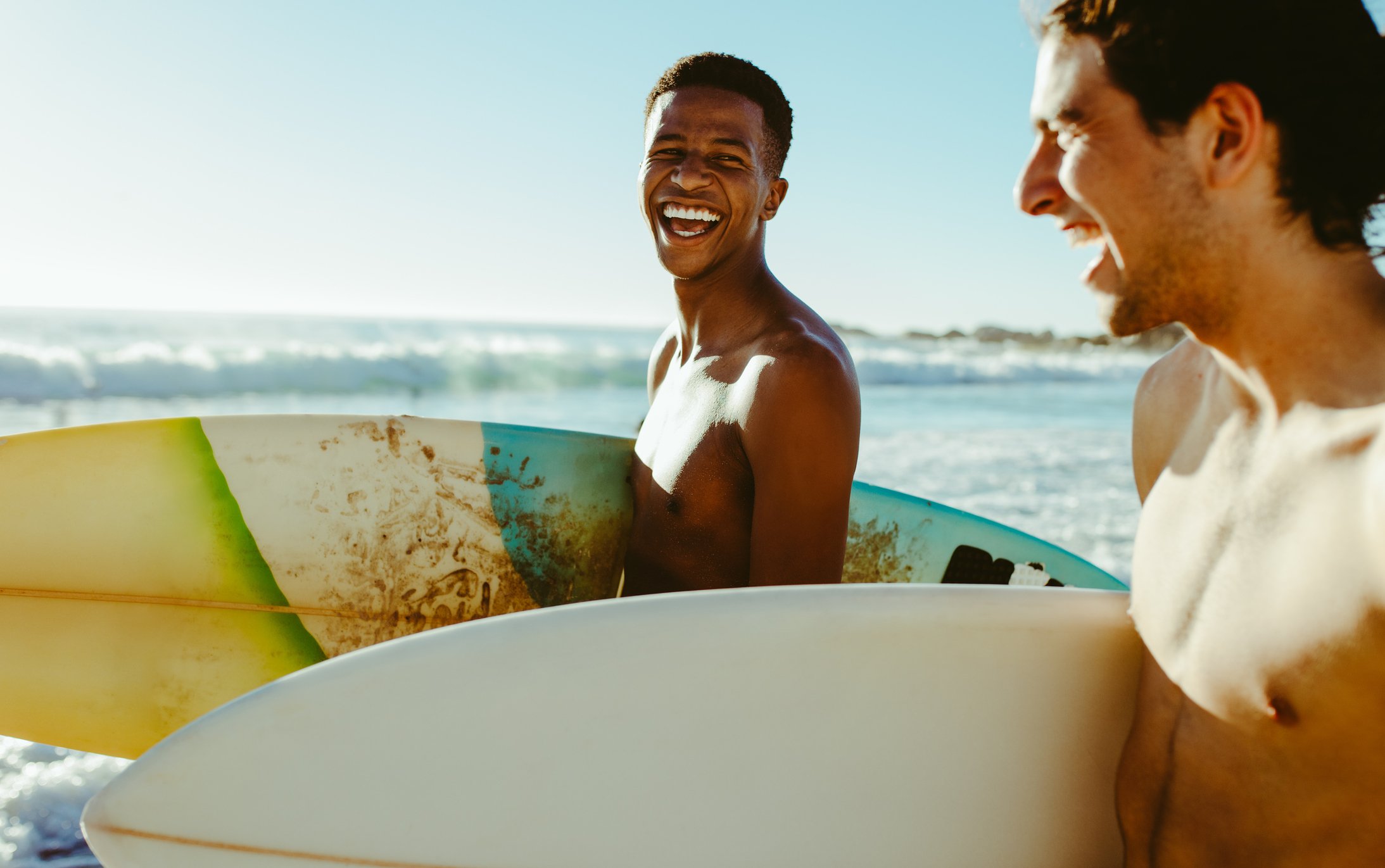Two happy men with properly proected skin and hair go surfing