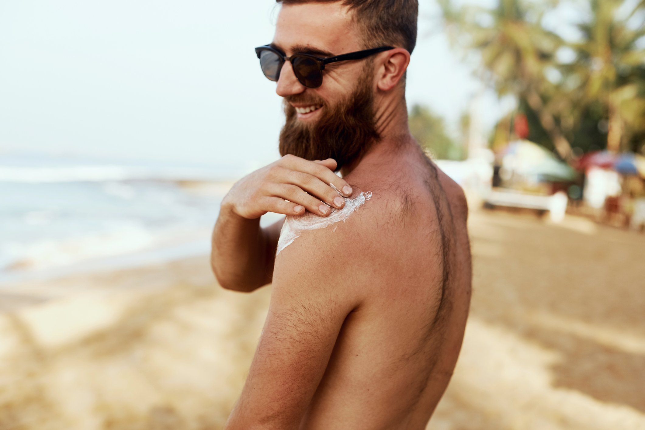 Handsome man with an impressive beard applies sun protection