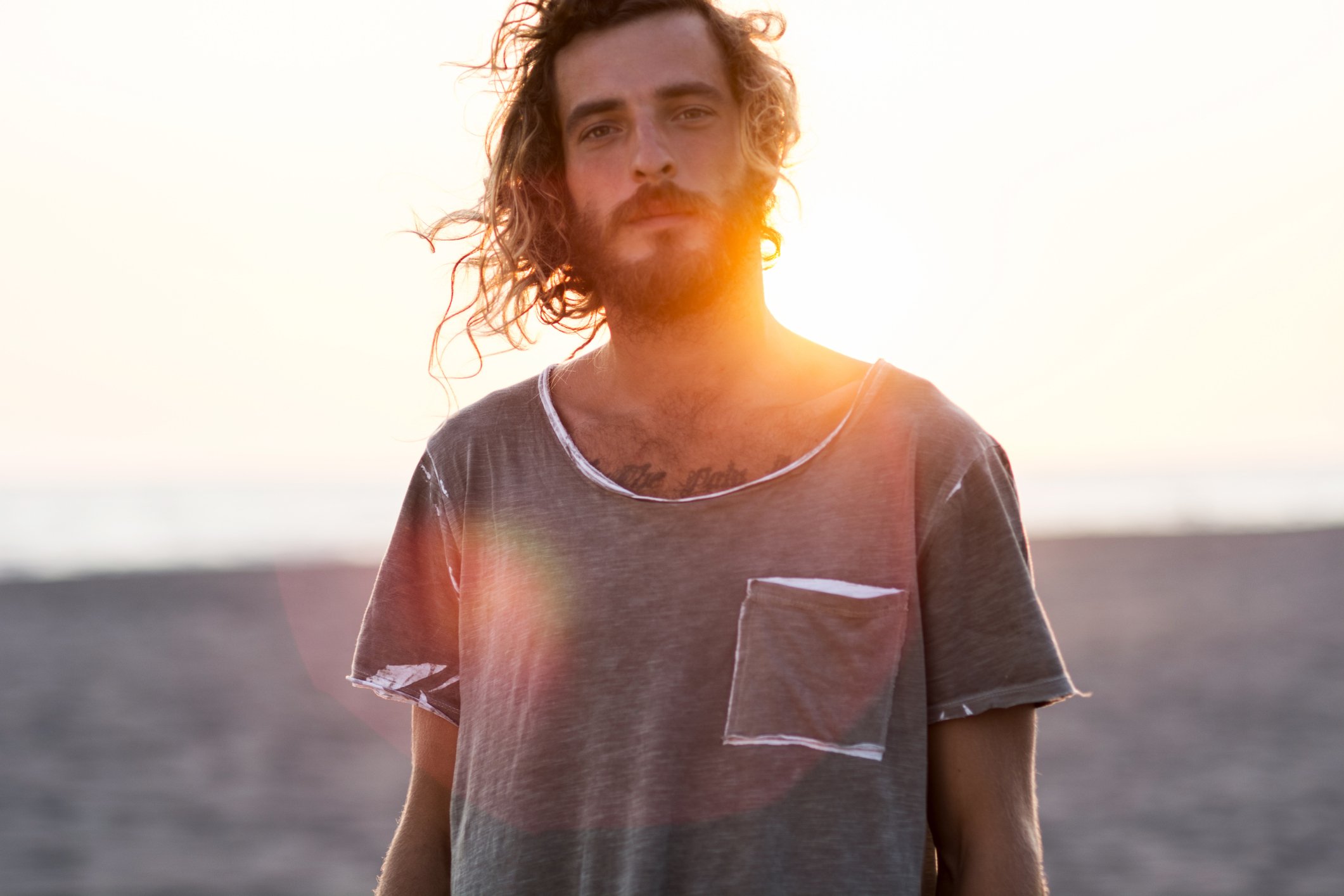 ortrait of man at the beach with a rugged beard and wind blowing through his hair