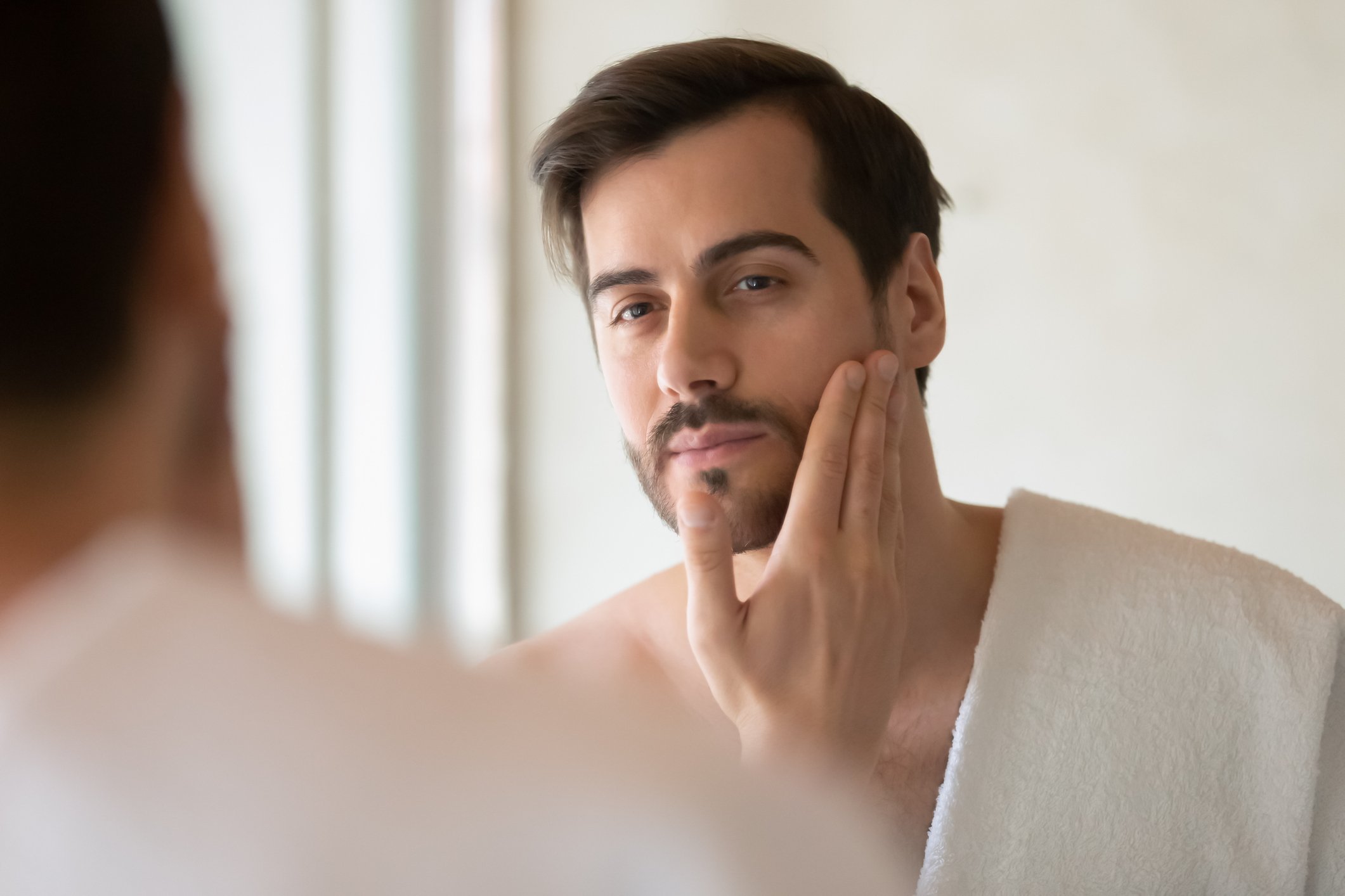 Young man caresses his beard after applying beard balm