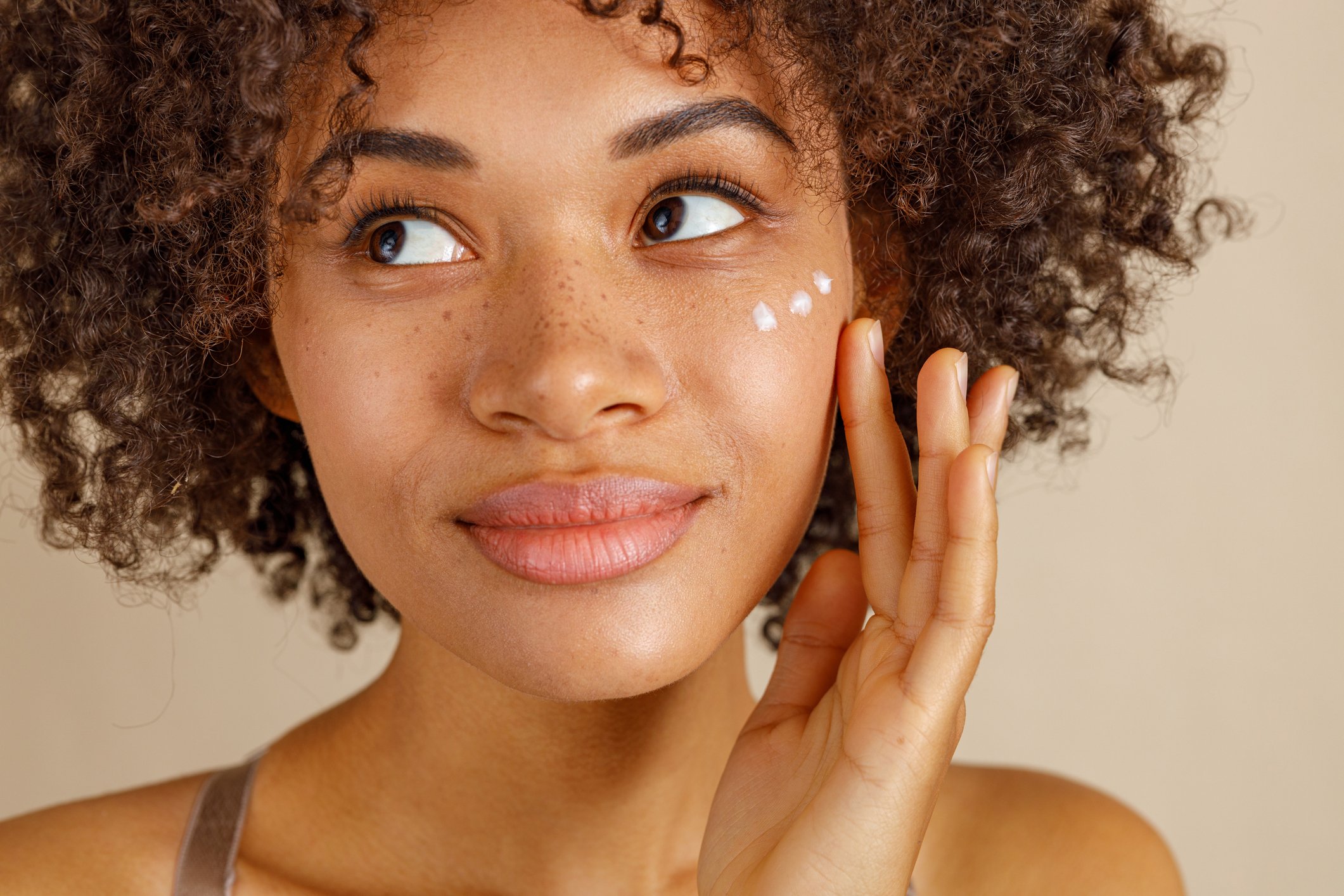 Woman applying cream to face as part of dermaplaning skincare routine | Venus UK
