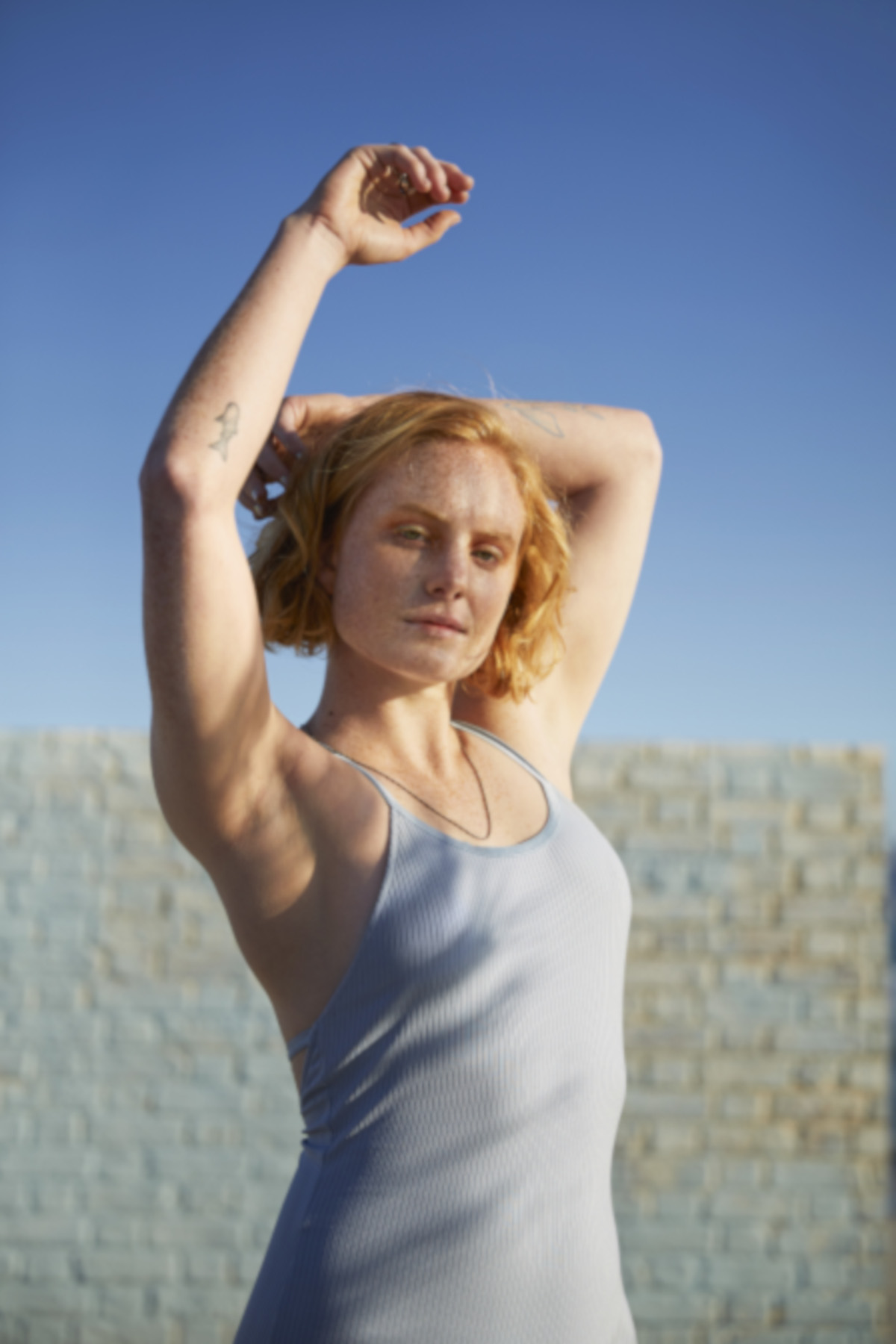 A woman wearing a lilac vest top raises her arms | Venus UK 