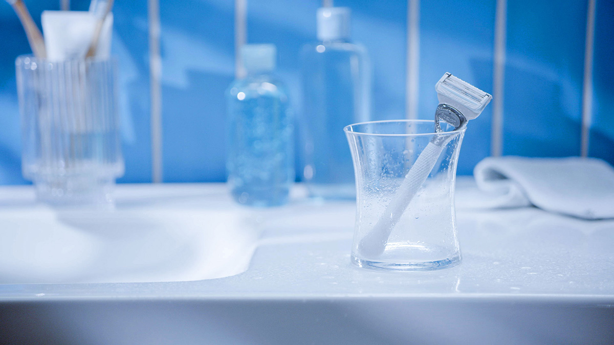 A white razor in a glass on the side of the bathroom sink | Venus UK