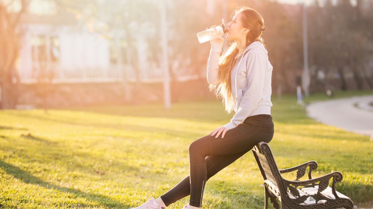 woman drinking protein shake during outdoor run