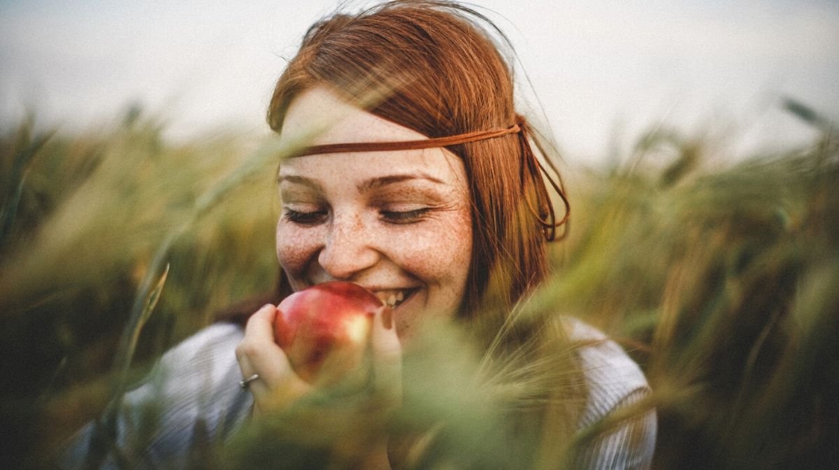 woman crunching into an apple - mindful eating should note the sound, taste, texture and smell of food