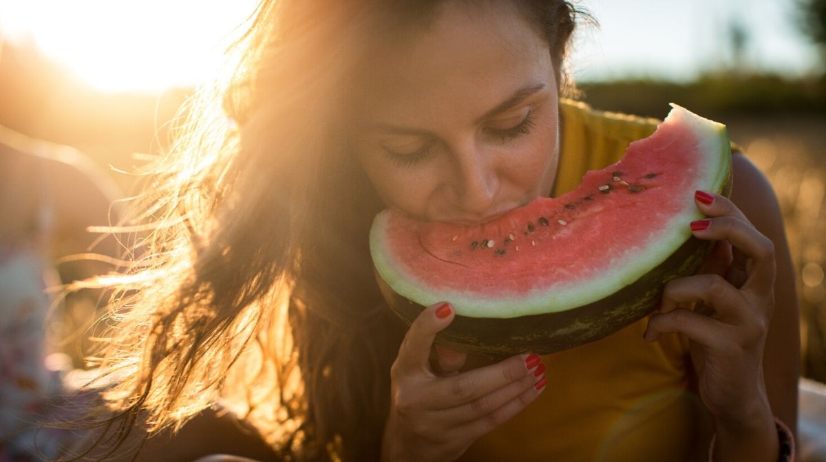 woman biting into a watermelon slice