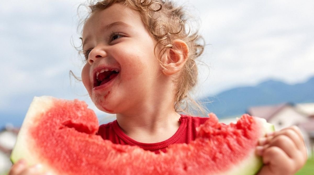 happy, healthy child messily eating a watermelon slice