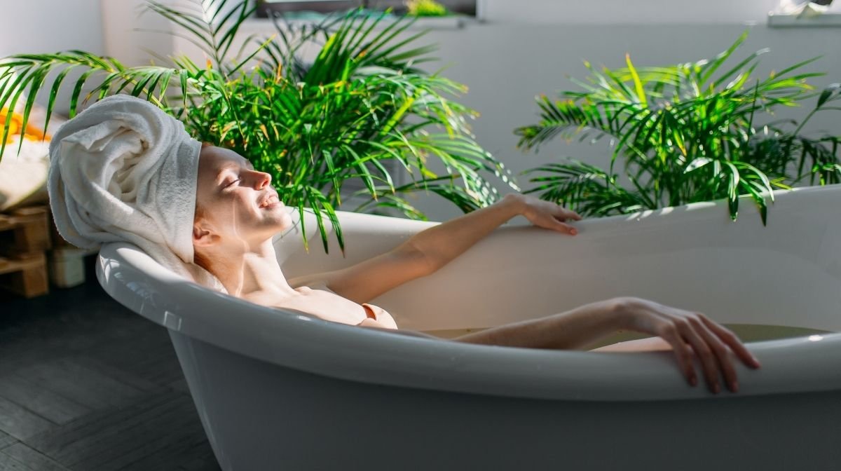 woman relaxing in bath surrounded by plants