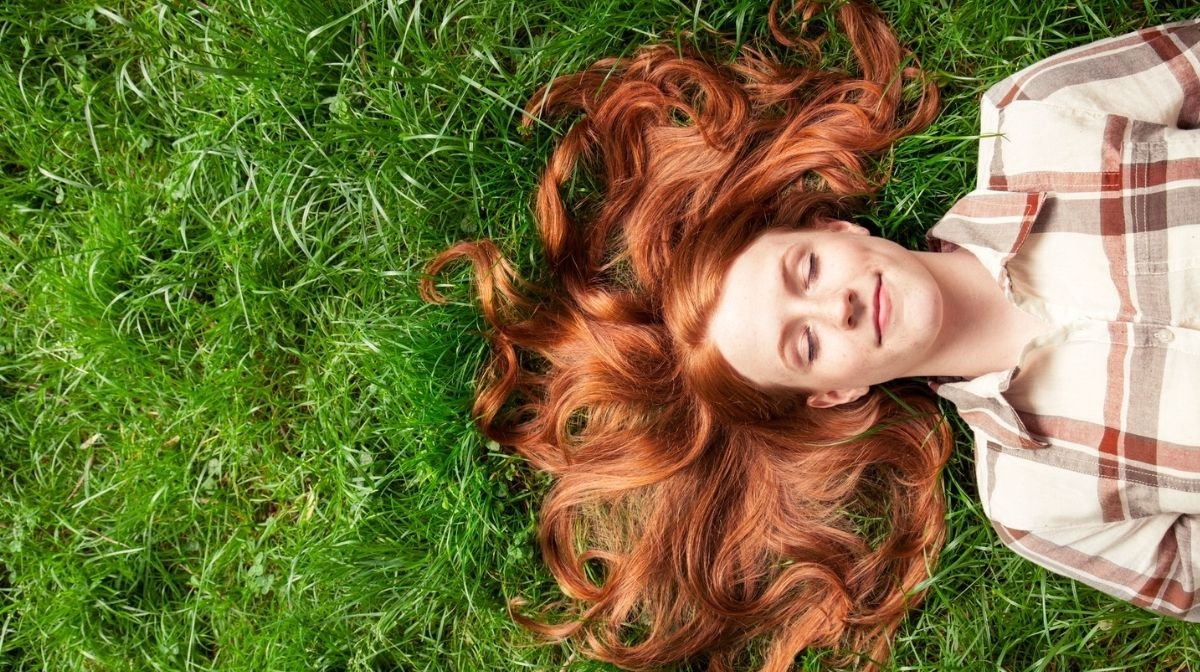 woman relaxing with her eyes closed while lying on grass