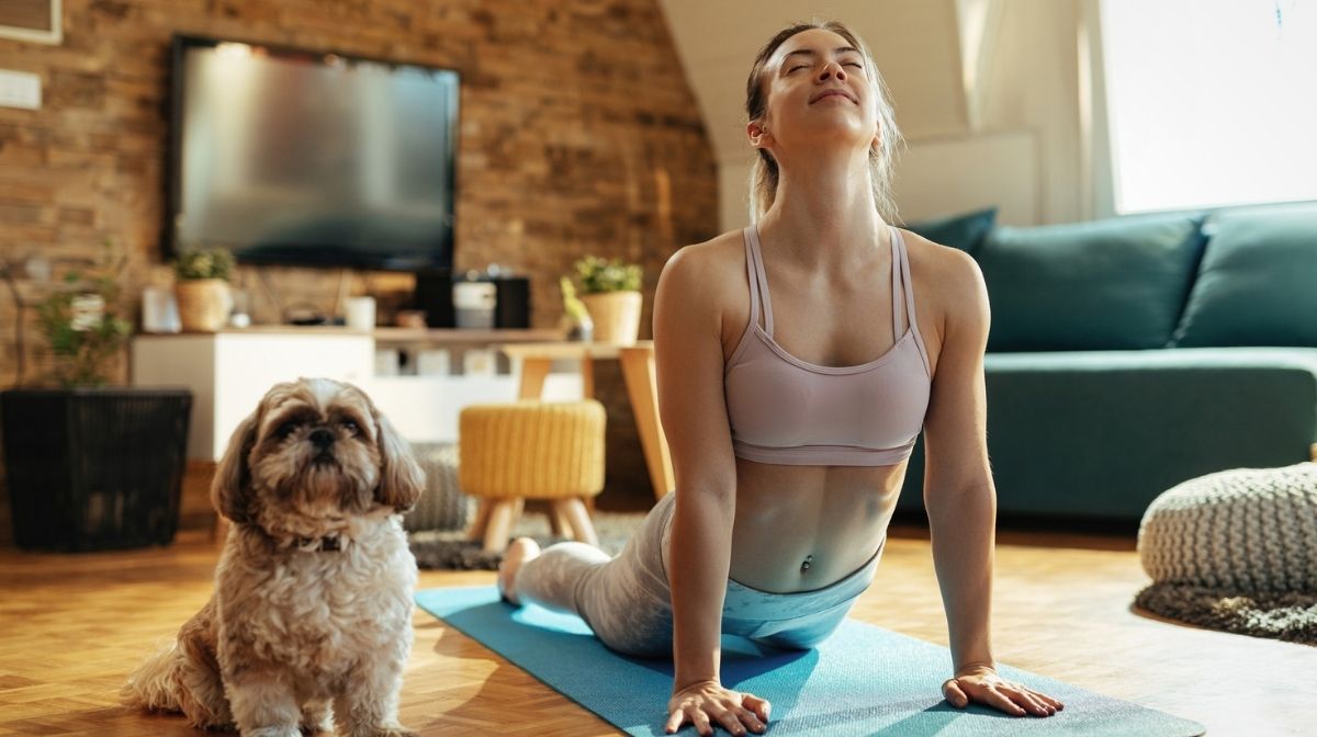 woman doing yoga stretches with pet dog