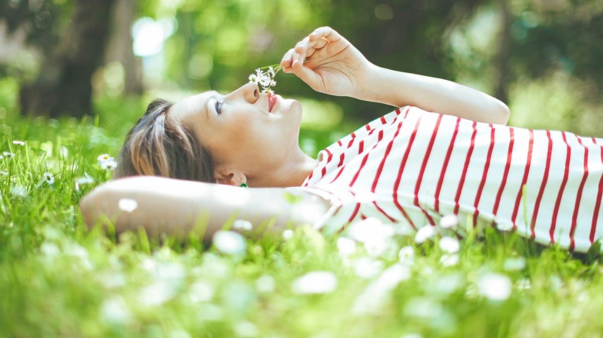 woman lying in grass, smelling flowers