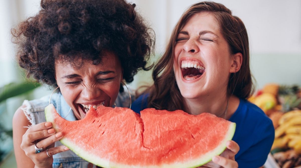 two women sharing a piece of watermelon