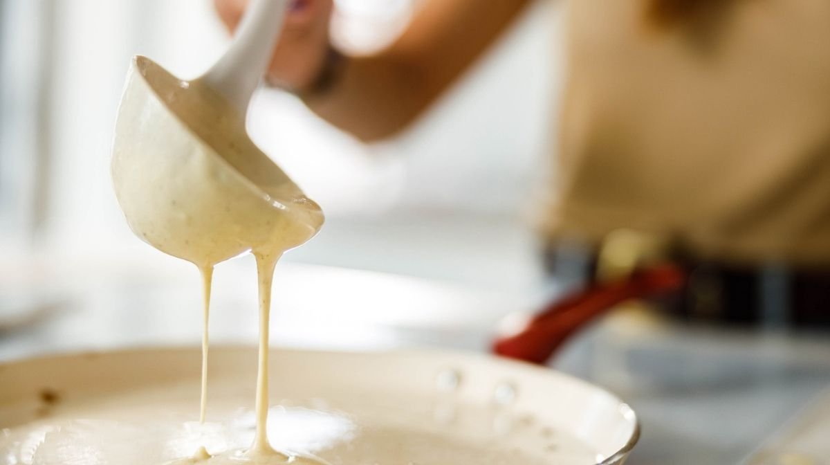 woman spooning pancake batter into a pan