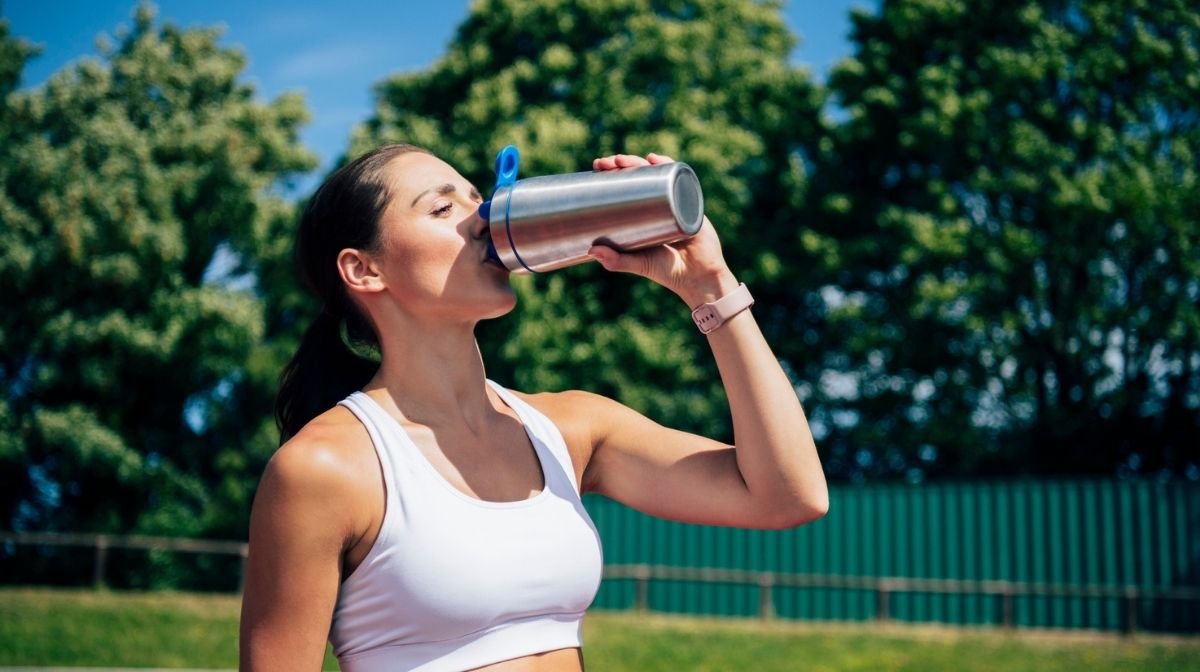 woman drinking a protein shake during a run