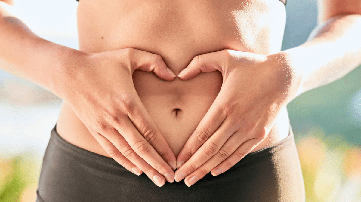 woman creating heart on her stomach, looking after her gut health