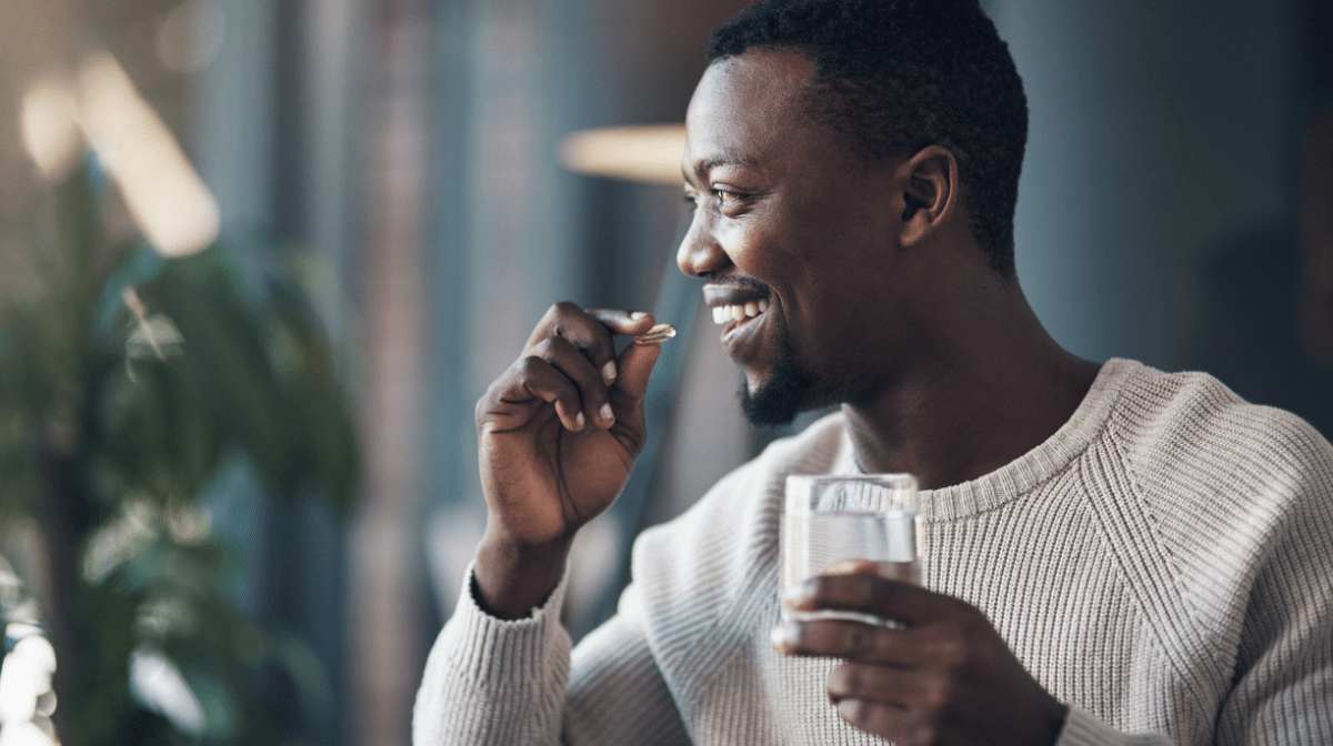 man smiling and taking men's health supplements