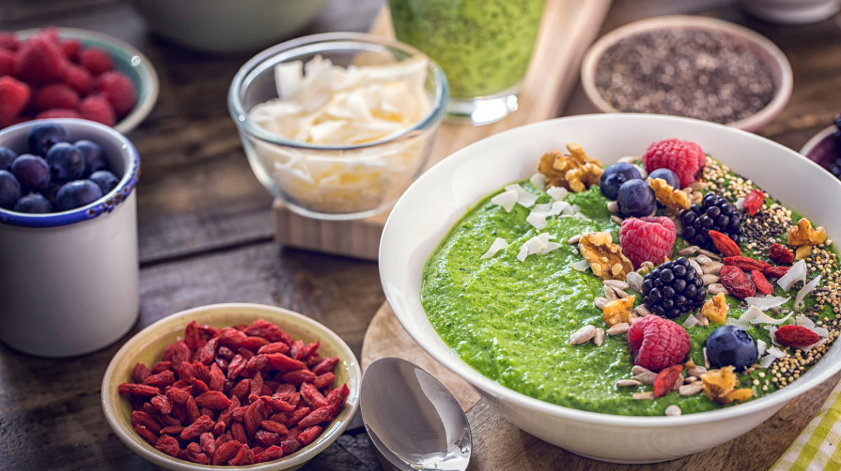 green superfood smoothie bowl with fresh fruit and granola on top