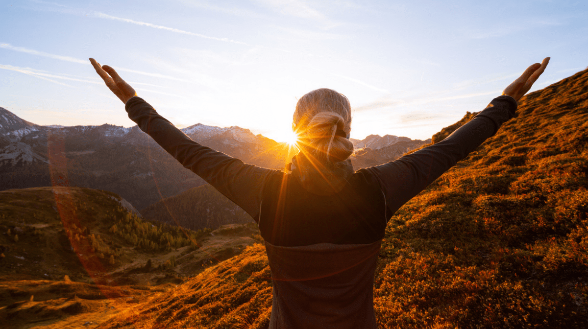 woman celebrating the sunrise at top of hill