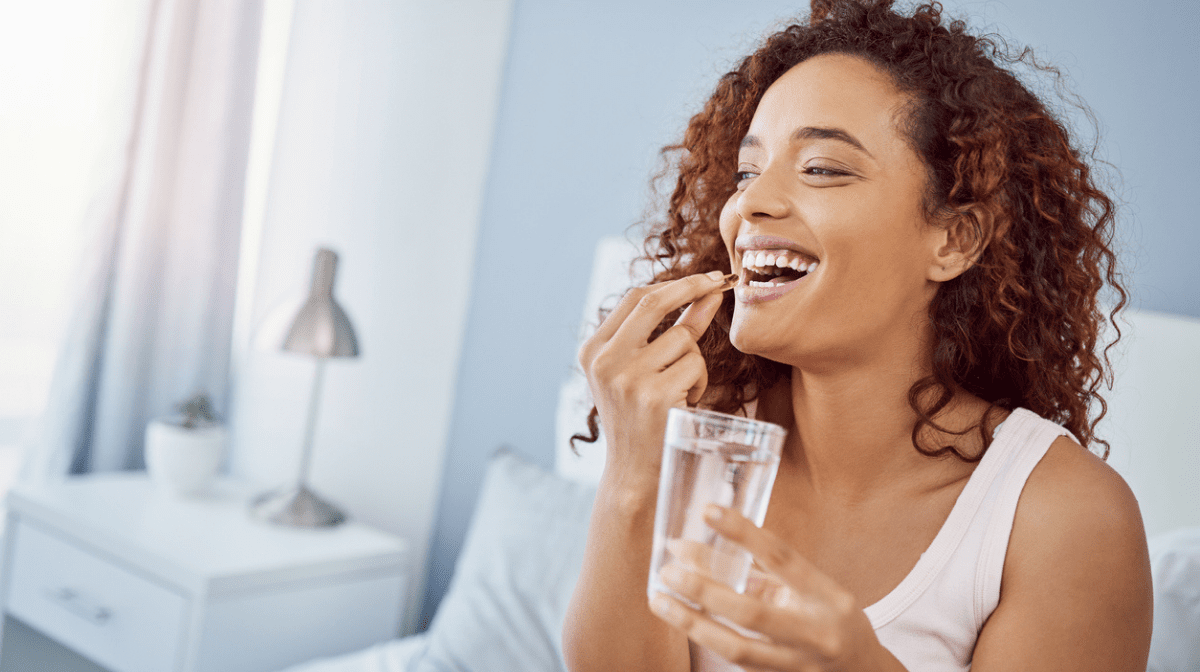 woman taking her daily vitamins with a smile