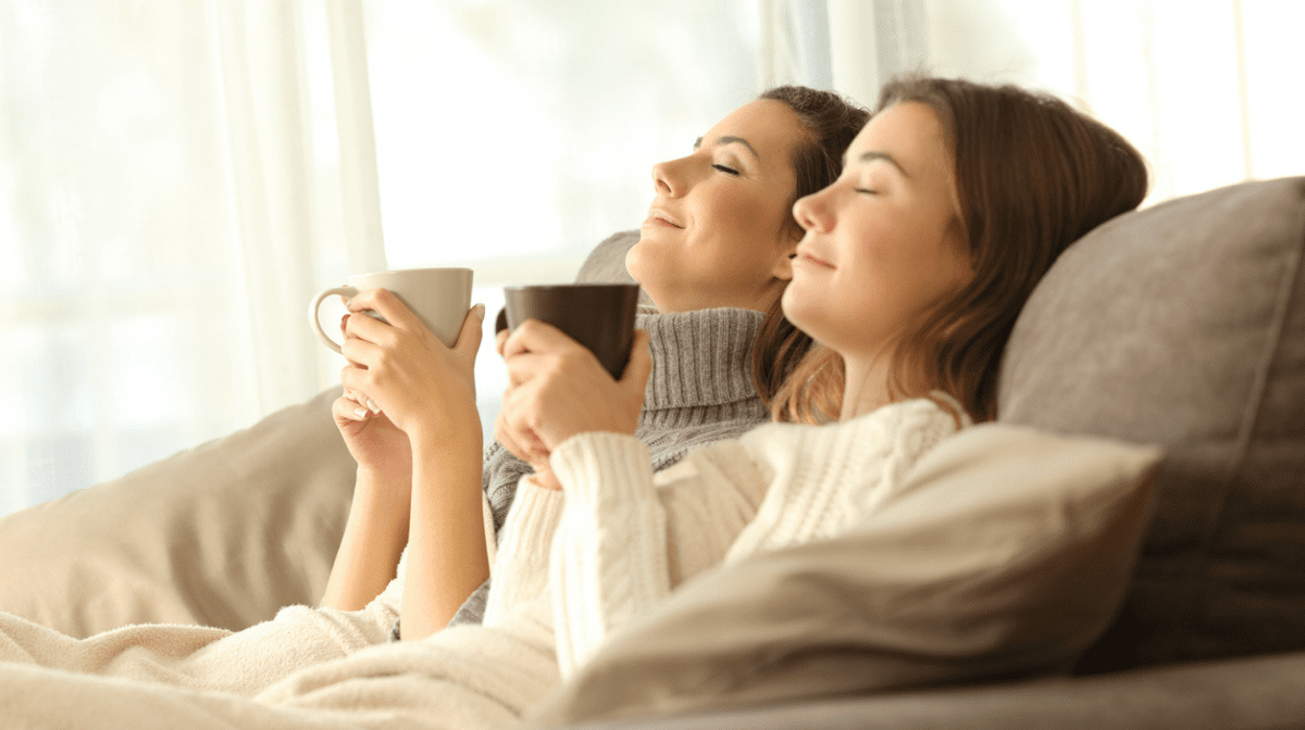 two women relaxing on sofa with cup of tea