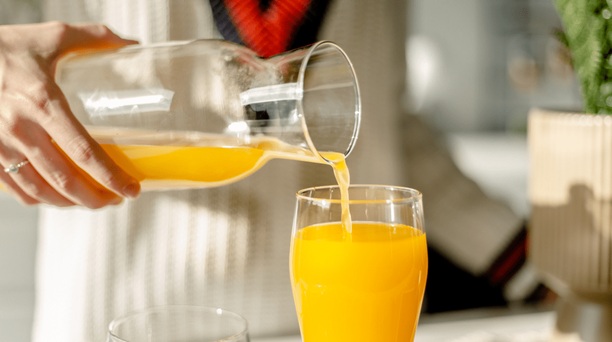 woman pouring orange juice into glass