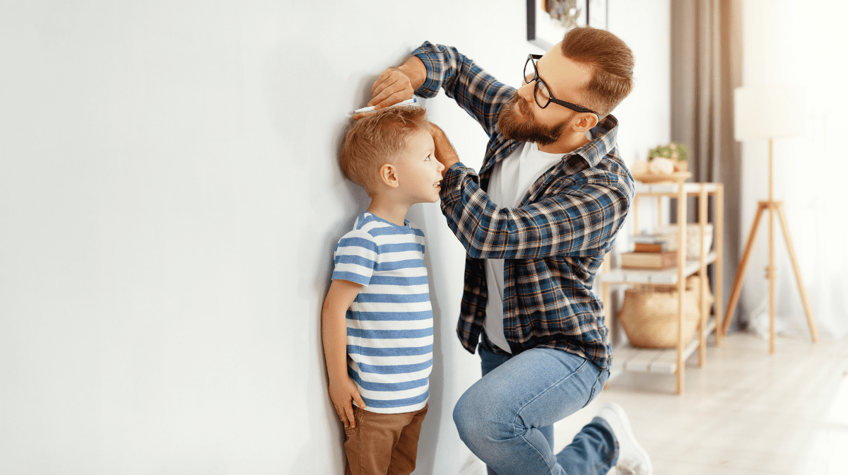 father measuring son's growth against wall