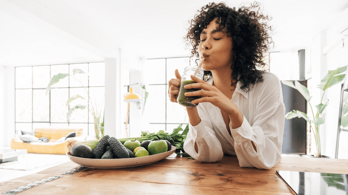 woman drinking green juice with leftover veggies and fruit