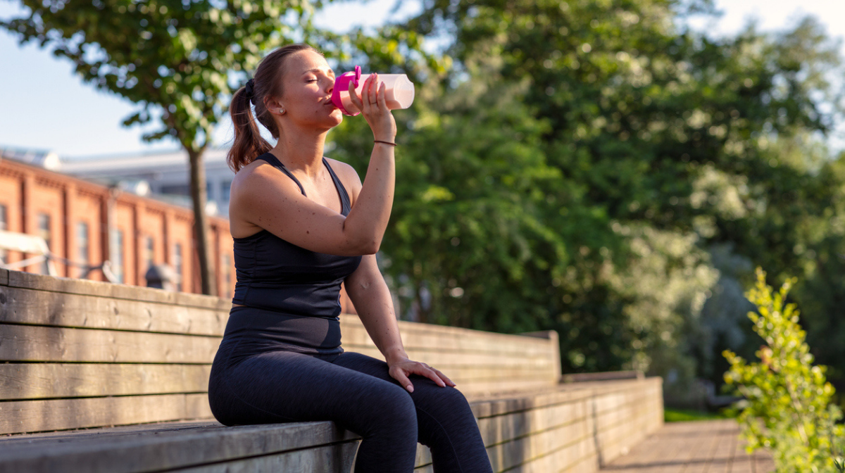 woman drinking protein shake outdoors
