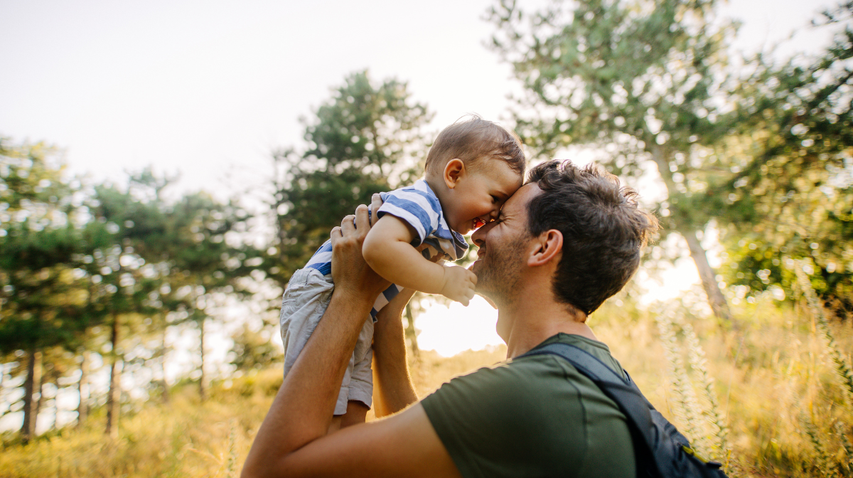 man holding up happy baby