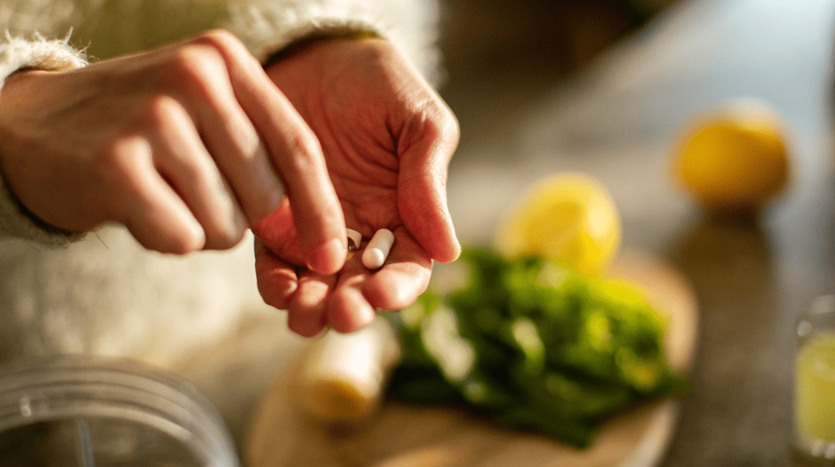 hands filled with three supplements, getting ready to take in the kitchen