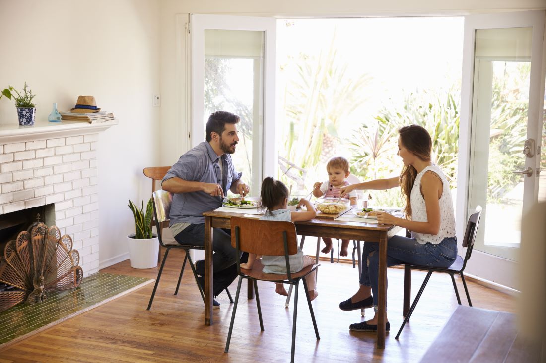 A family of four sat around a dining table eating a meal.