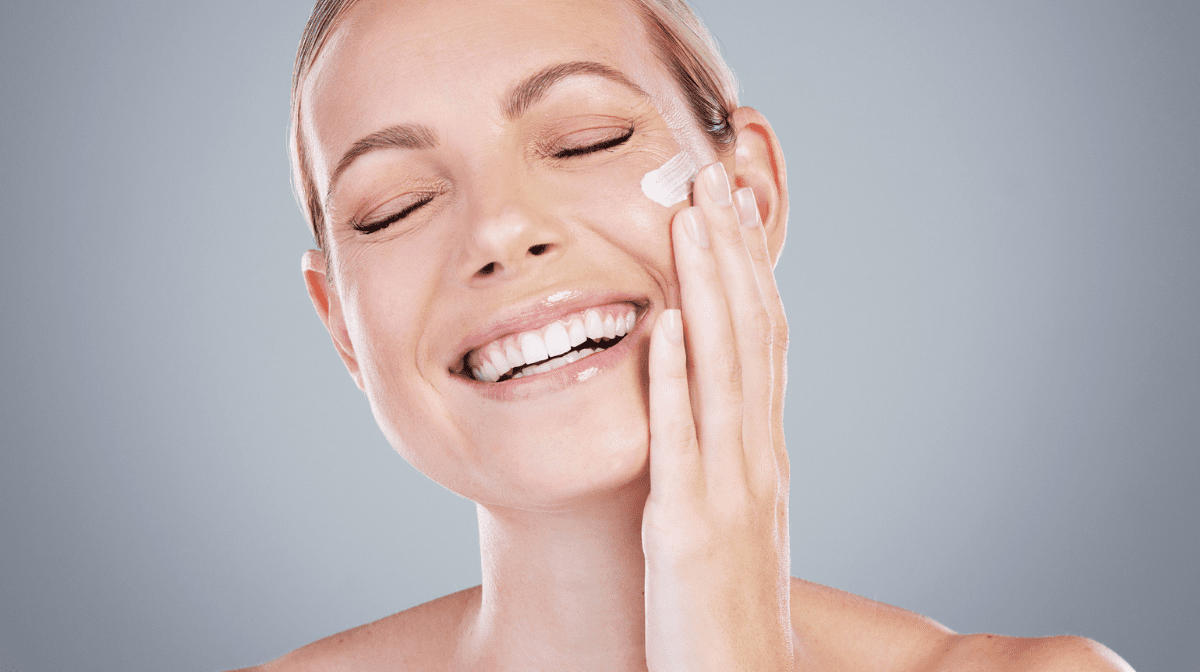 Woman applying face cream while smiling