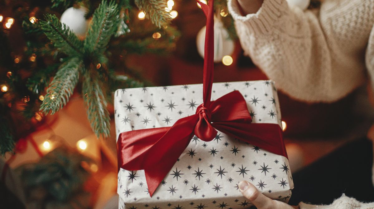 A woman unwraps a holiday gift.