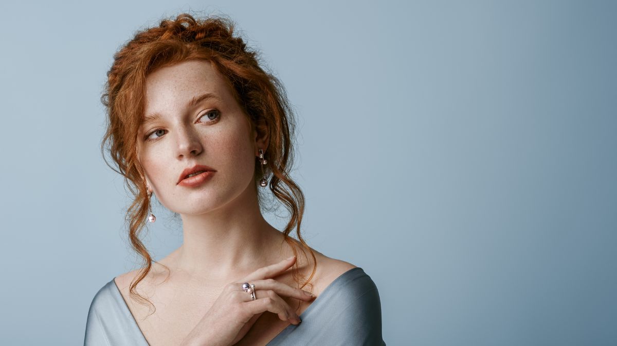 A young woman on a blue background with a soft glam makeup look.