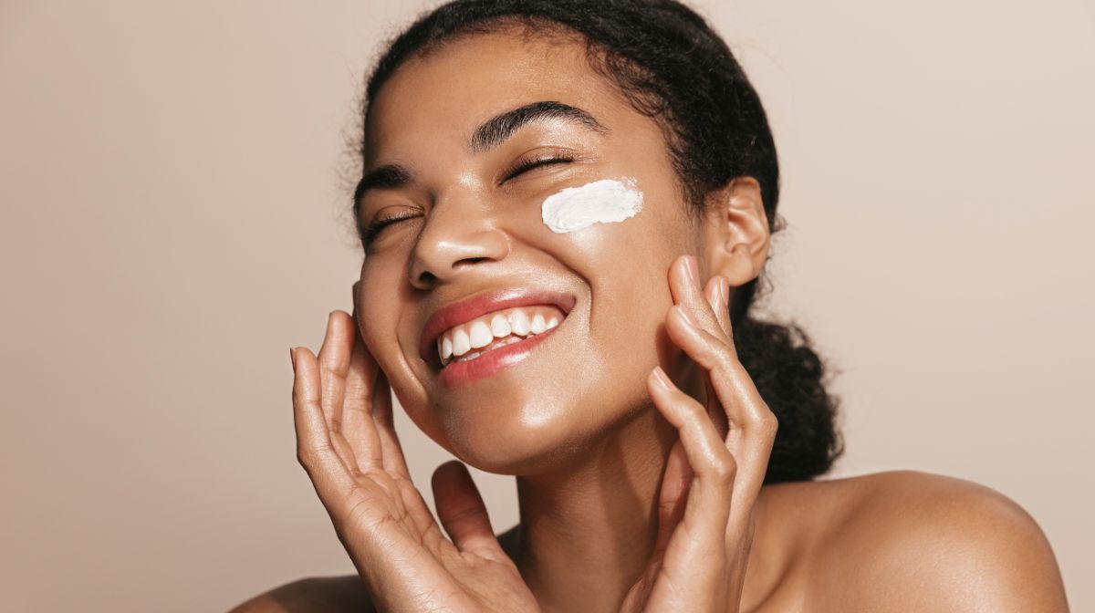 A young woman applies skincare to help improve her skin texture.