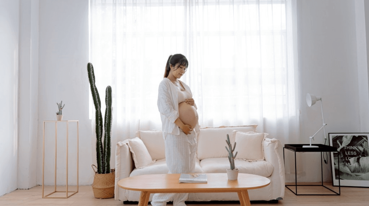 A pregnant lady holding her baby bump in her living room