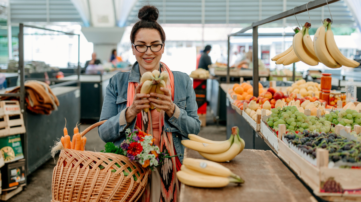 A woman buying bananas in the grocery shop. 