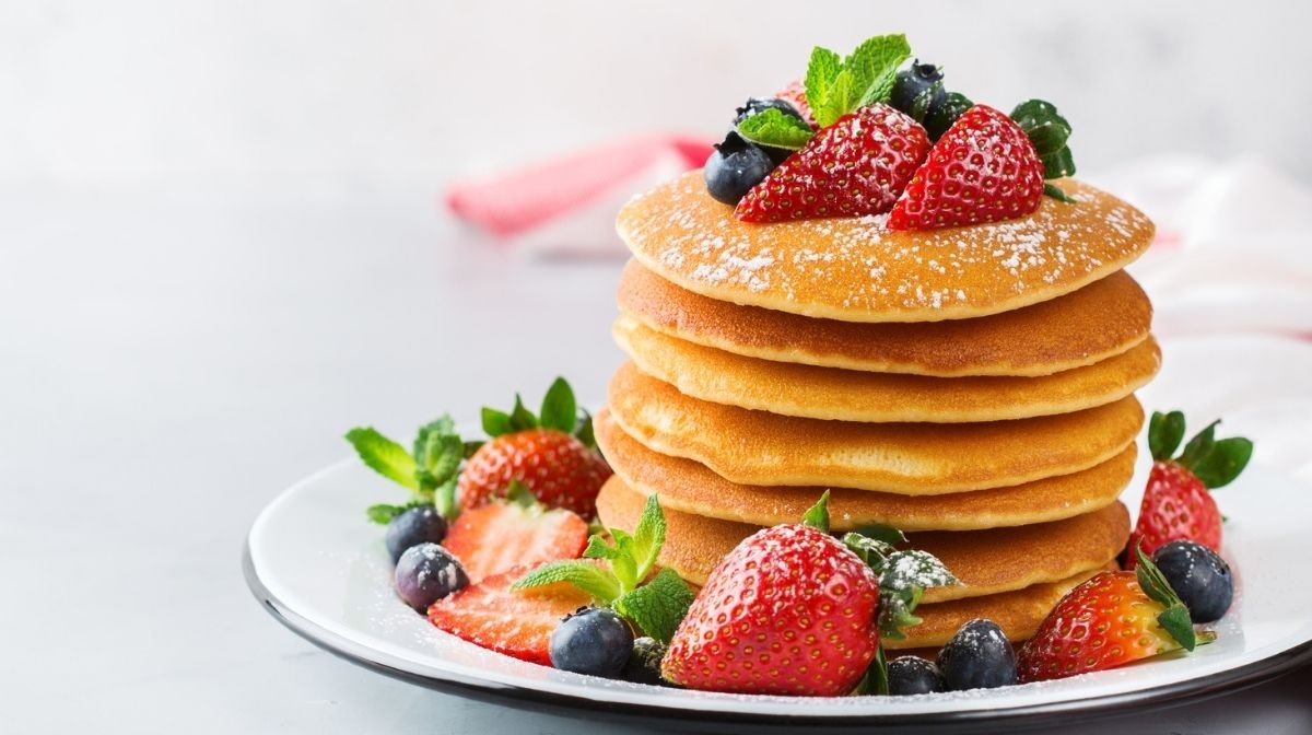 stack of pancakes topped with fresh fruit
