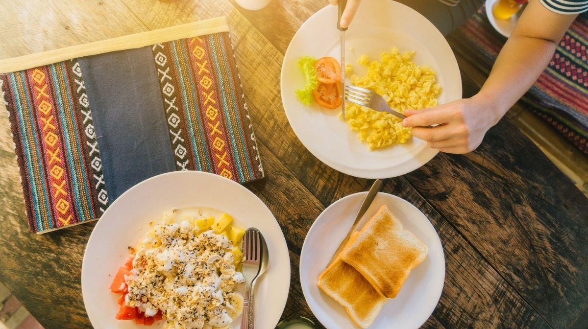 woman eating scrambled eggs and toast for breakfast