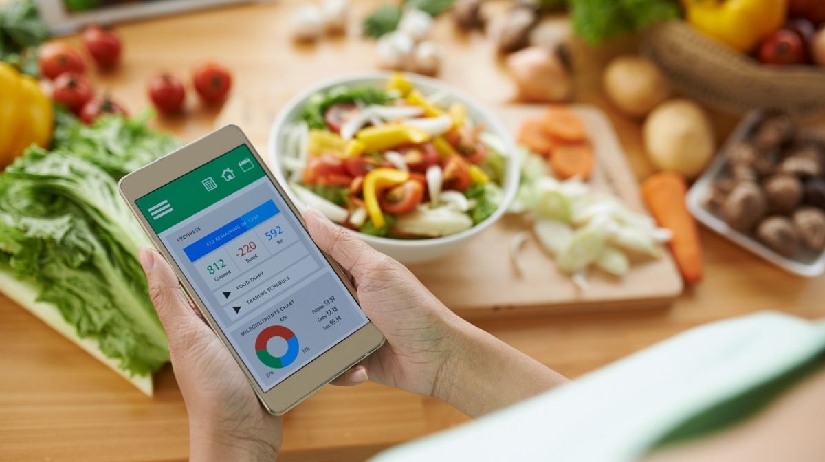 woman looking at calorie tracking app while preparing food