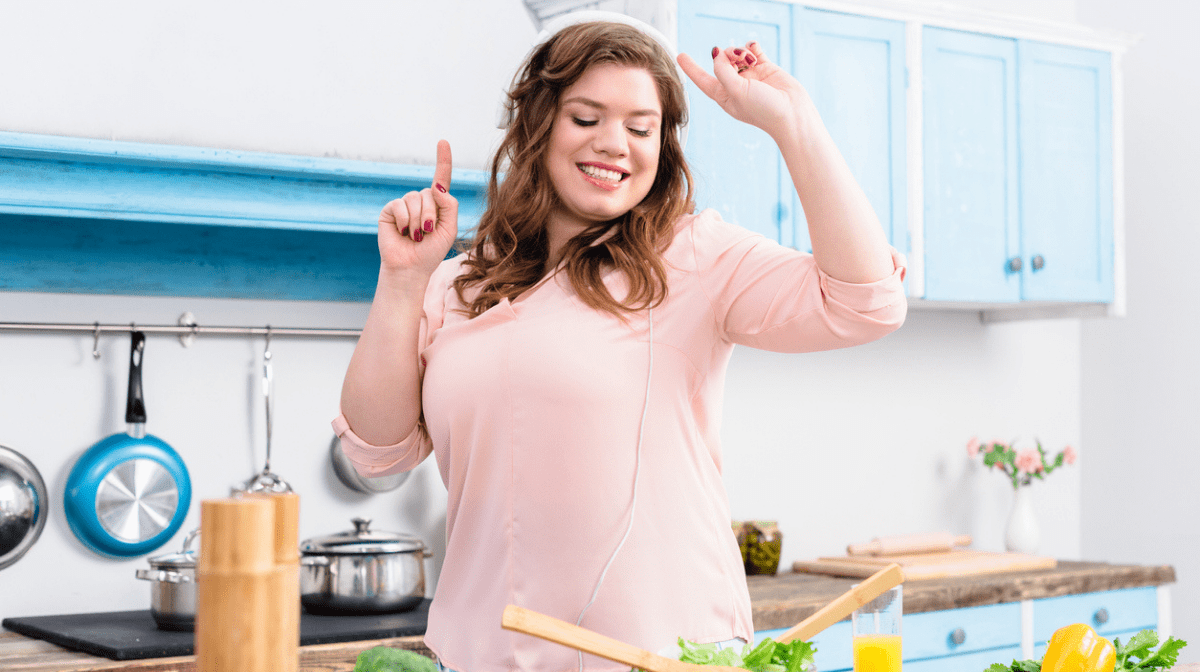 woman dancing in kitchen while making salad