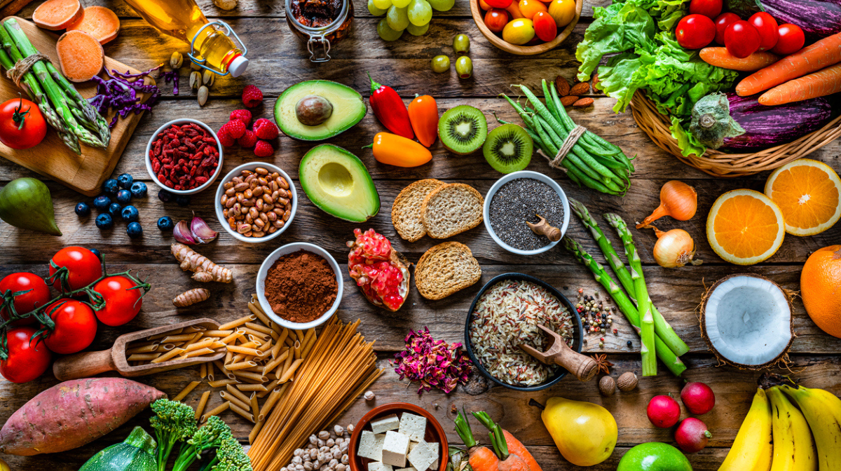 A table full of healthy food, including vegetables, crops, nuts, fruits and berries. 
