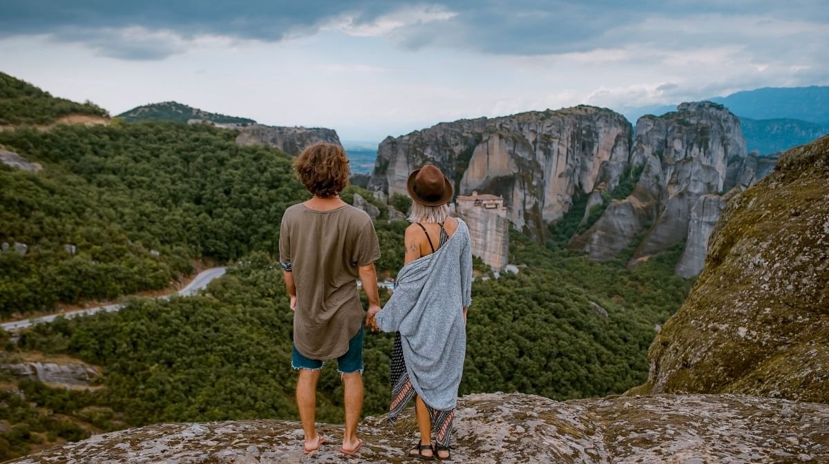Una giovane coppia che si gode la vista delle montagne coperte di alberi verdi.