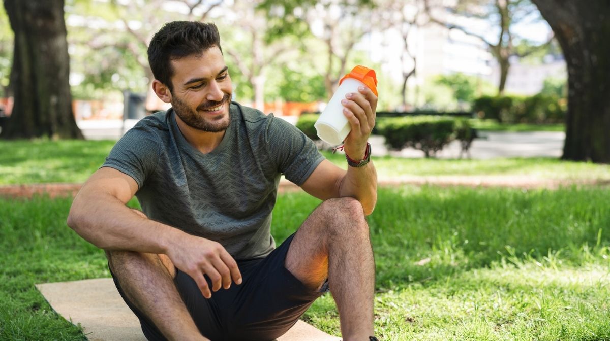 man drinking protein shake outdoors