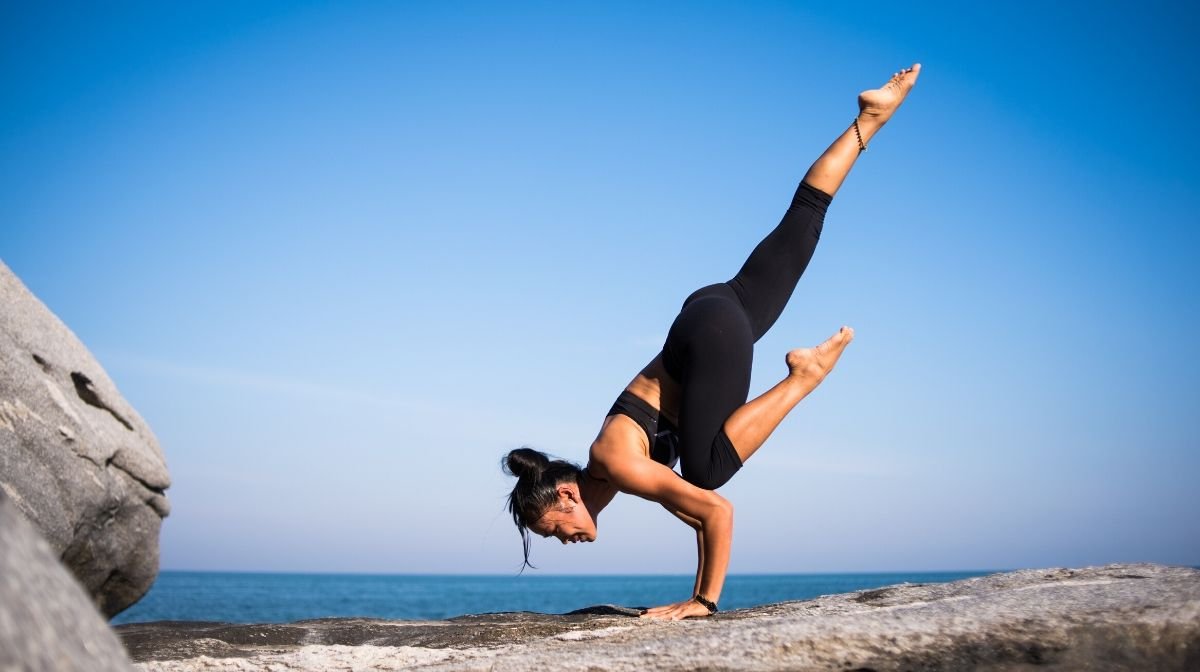 woman doing yoga handstand by the sea