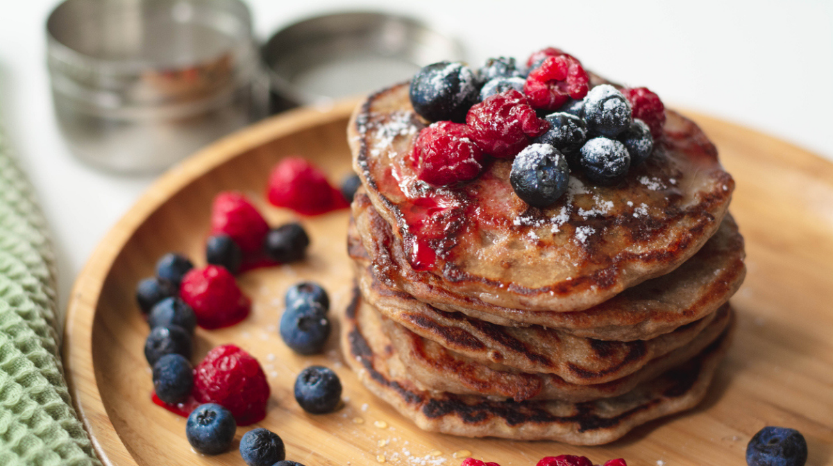 pile of homemade protein pancakes with berries and maple syrup