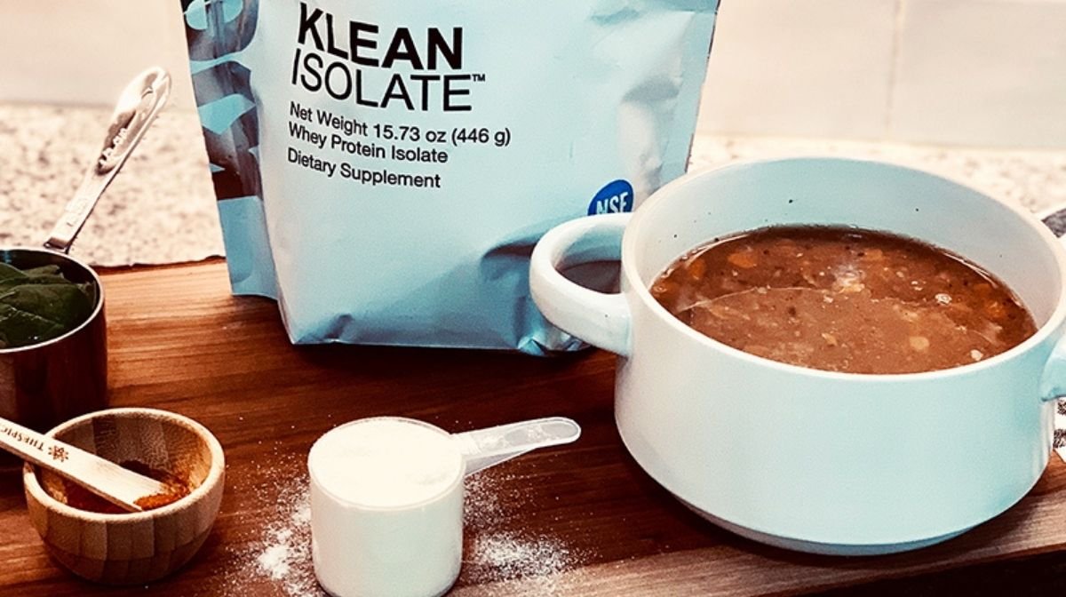 A bowl of Lentil & Spinach Soup next to a pouch of Klean Isolate