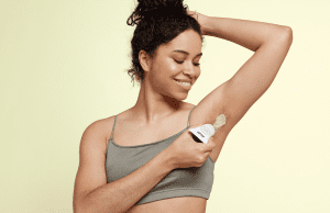 women applying the pit deodorant while smiling 