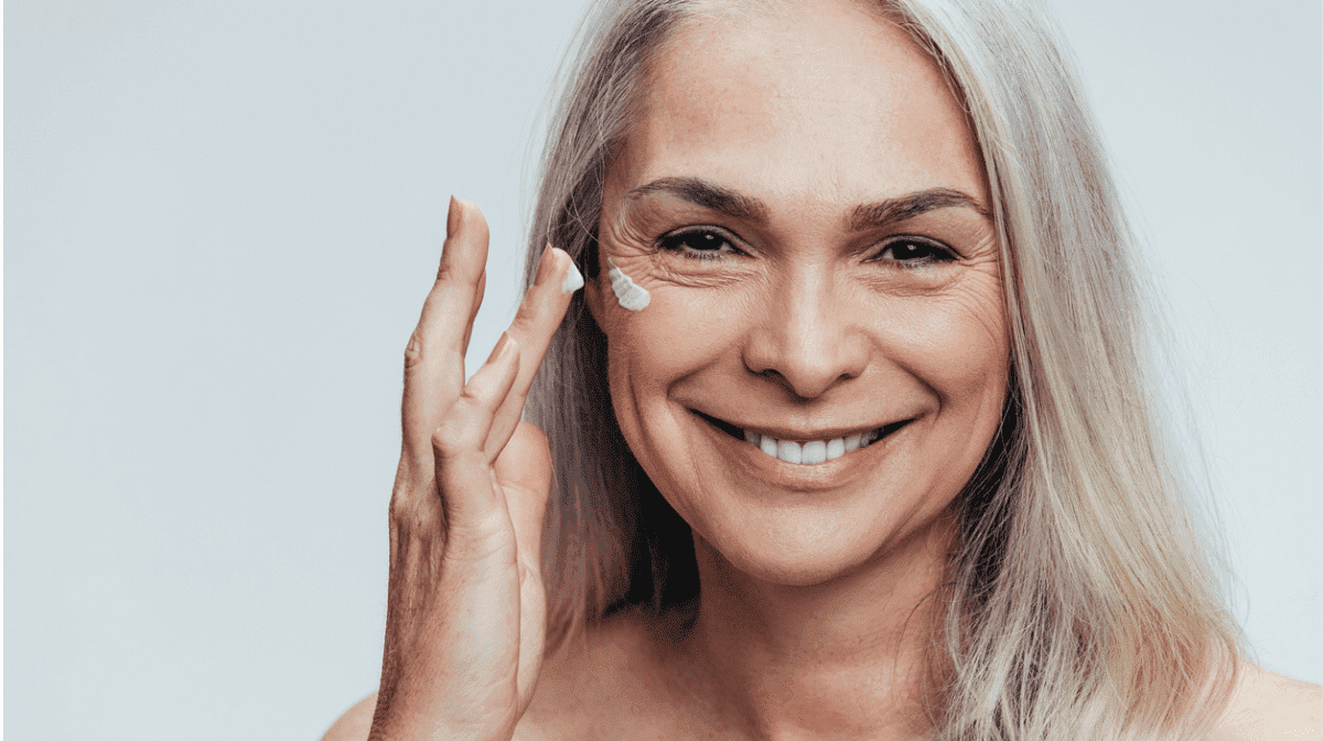 Woman applying face cream to cheekbone