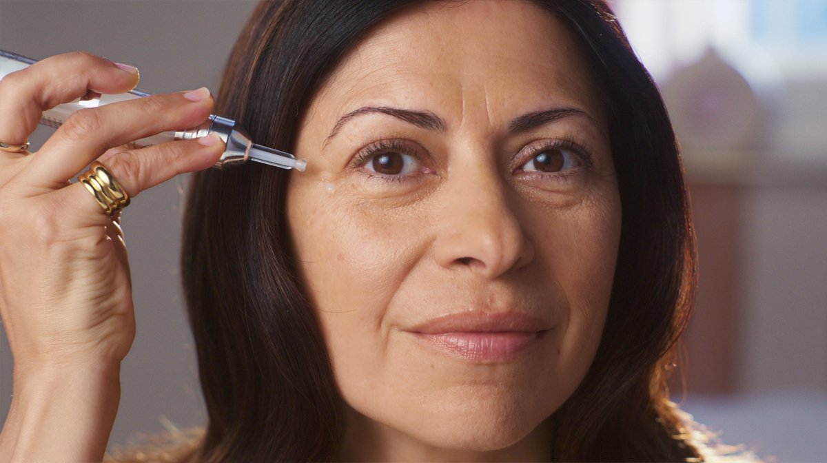 Close up of a woman applying No7 Laboratories Line Correcting Booster Serum to cheekbone
